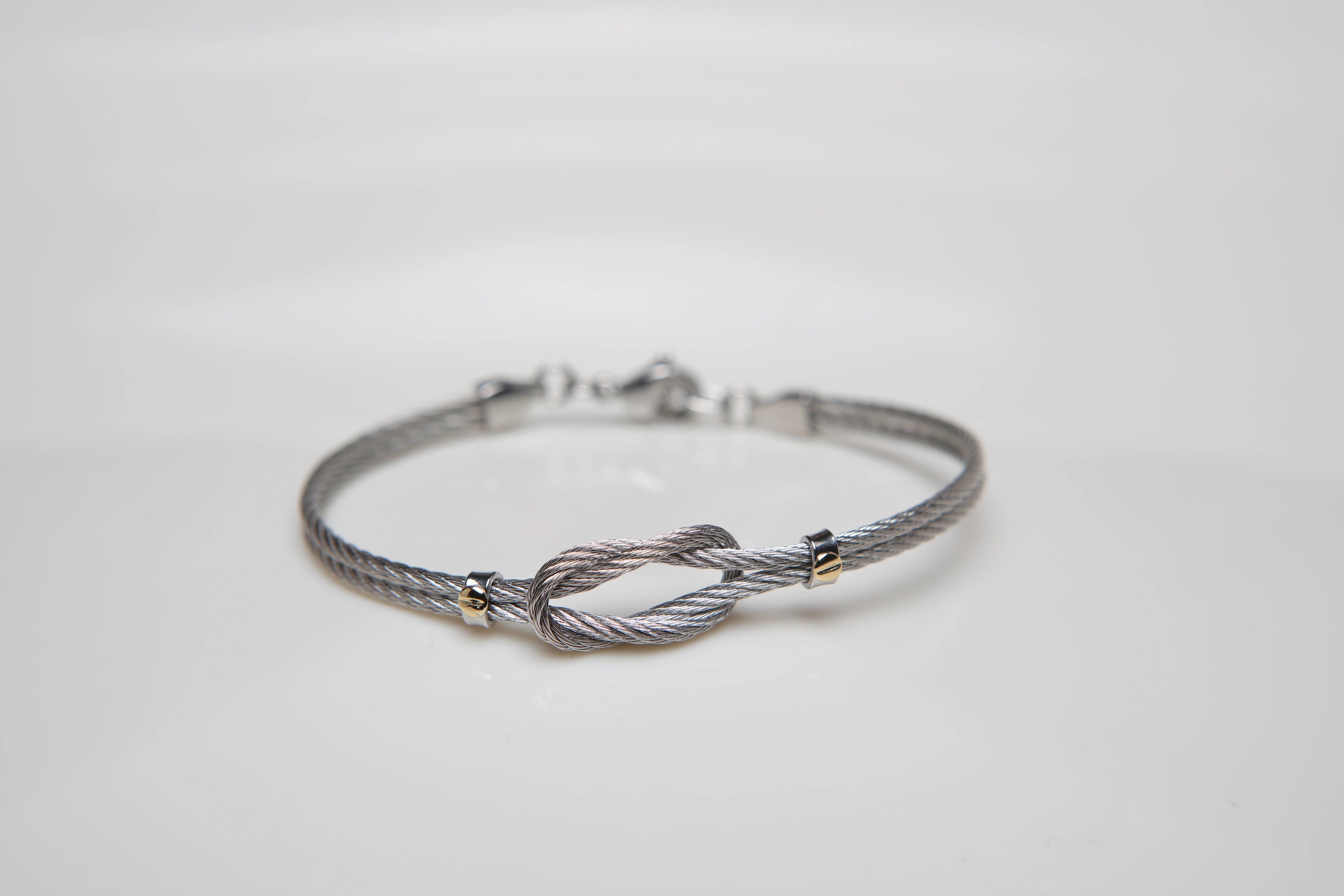 Stainless steel cable bracelet with knot and screws in 18kt gold