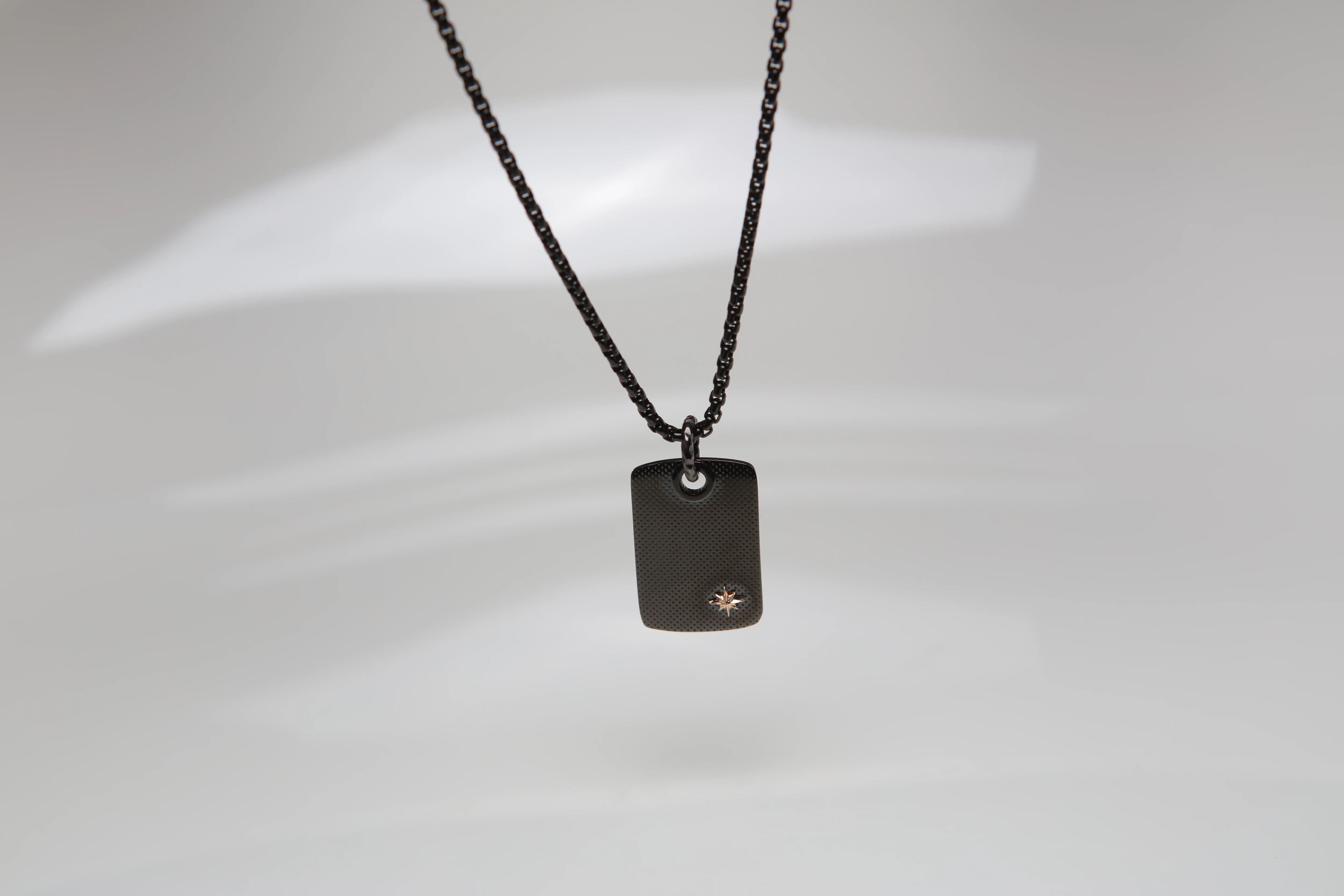 Necklace with knurled plate pendant in black PVD and polar star in rosé